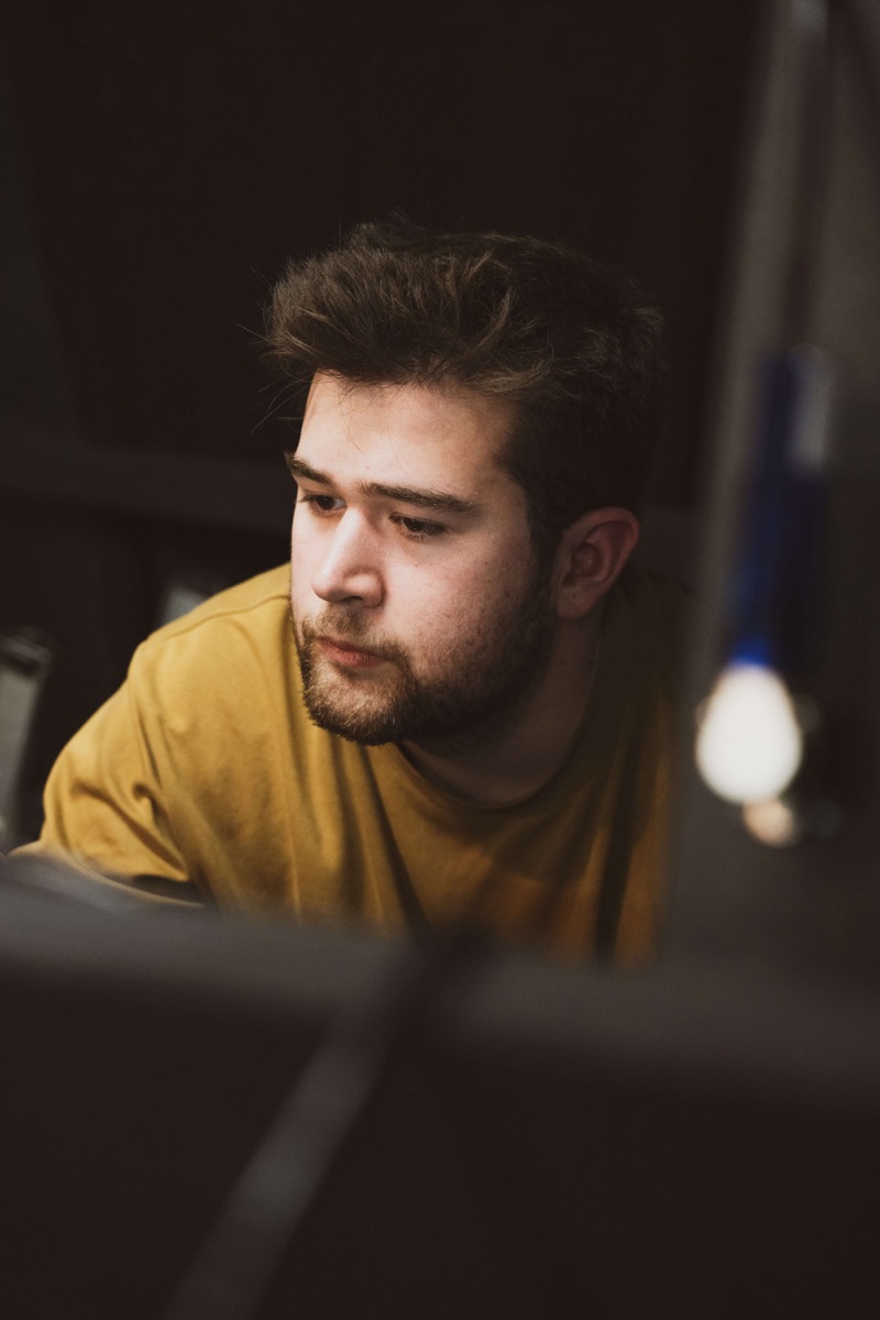 Dan Light at a production desk in a darkened theatre, lit by a monitor's glow as he concentrates on his work.